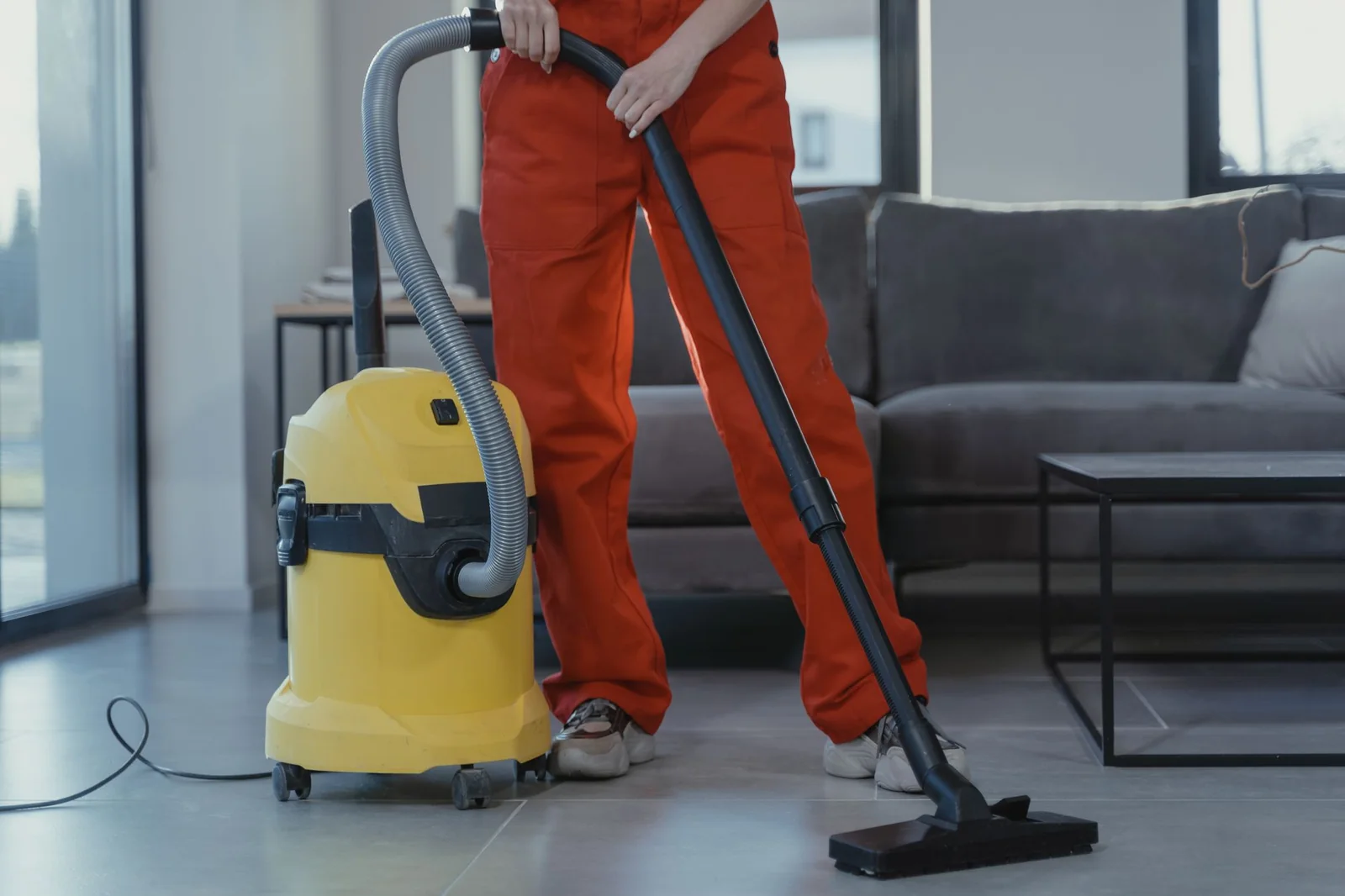 Cleaner in uniform vacuuming a hard floor with a commercial wet-dry vacuum