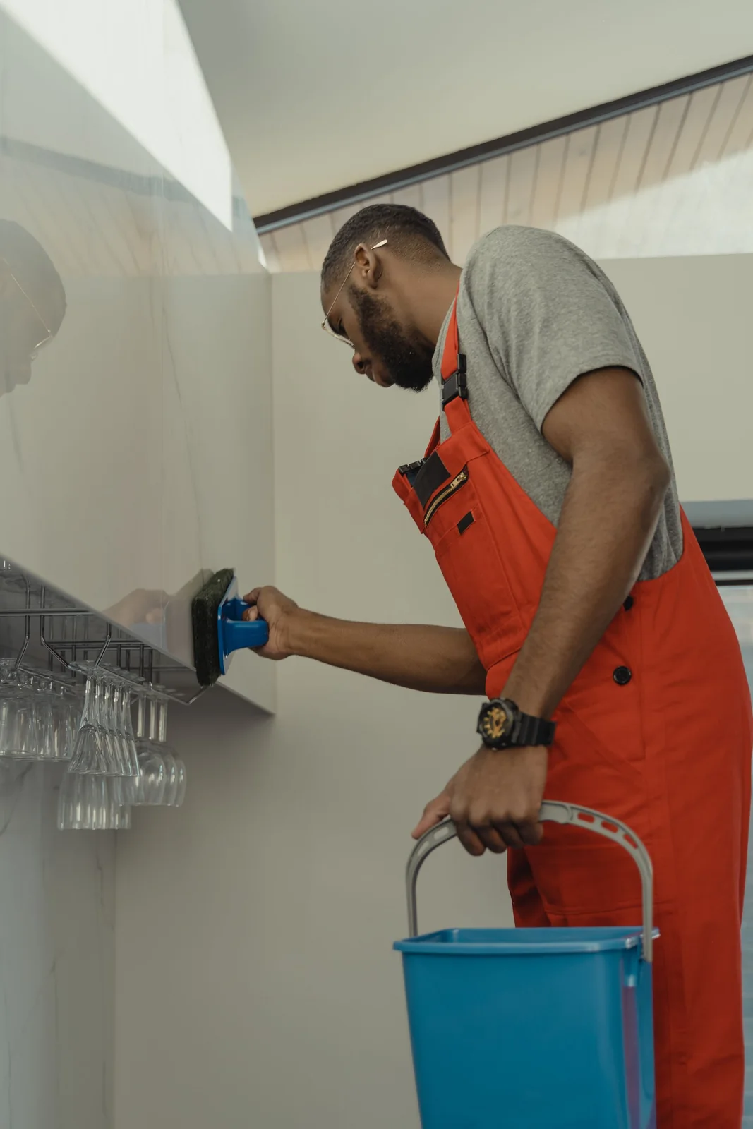 Cleaner wiping down a wall with a bucket of cleaning solution