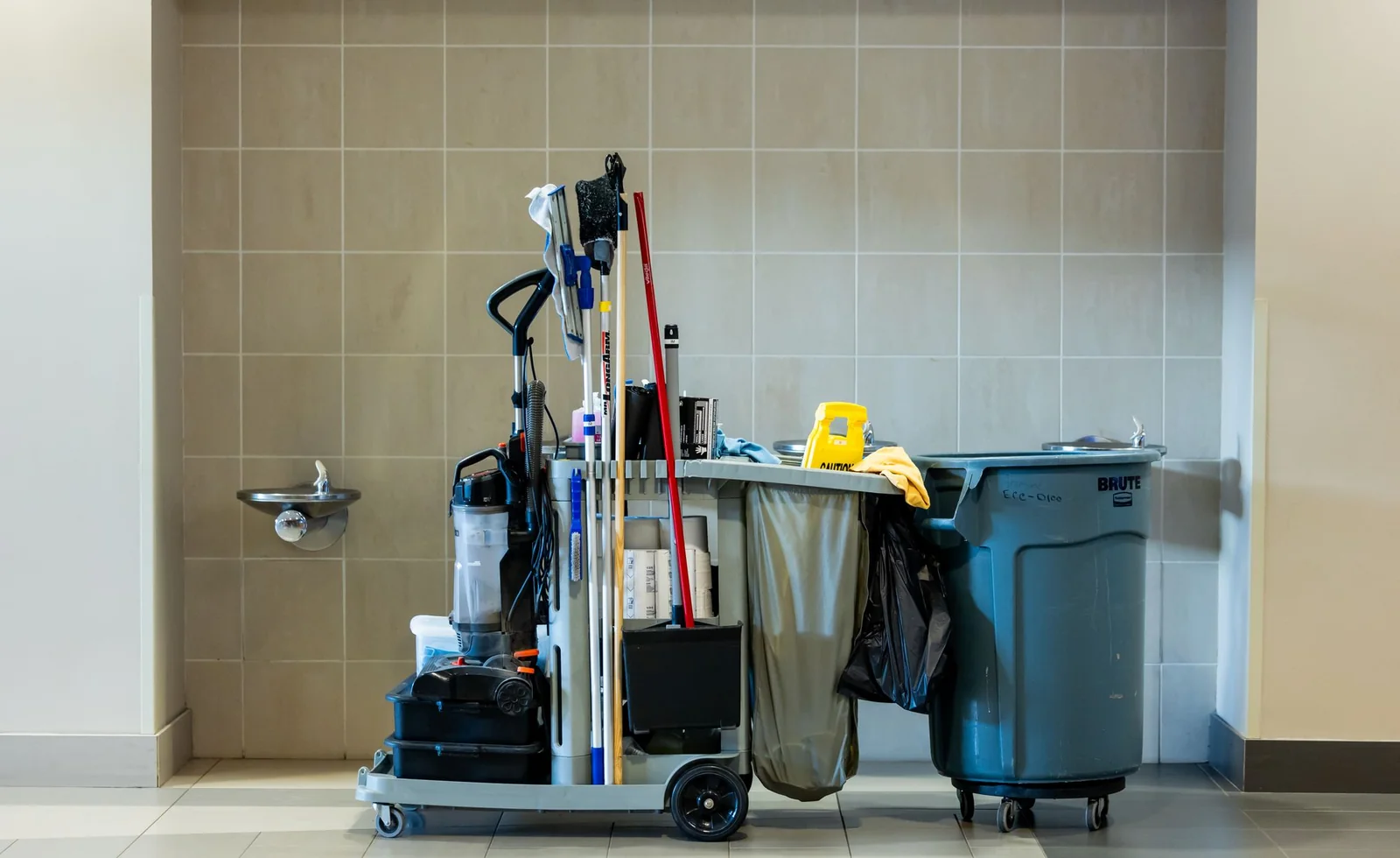Janitorial cart with mop bucket and supplies staged in a commercial building