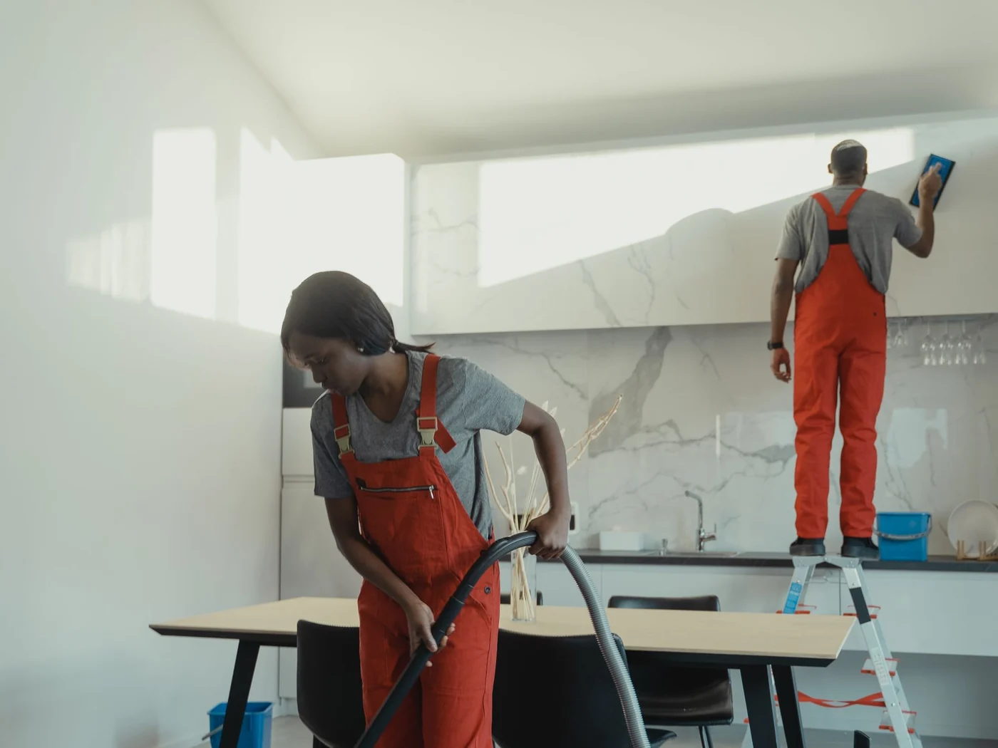 Two cleaners vacuuming and wiping down a newly finished interior after a build