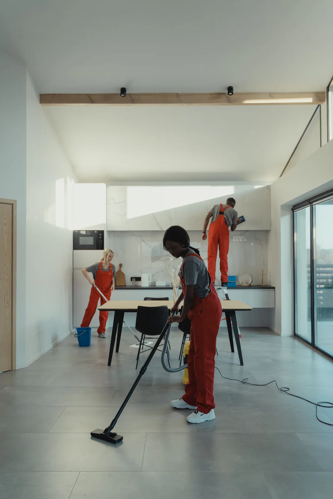 Cleaner mopping the floor of a bright, modern kitchen area