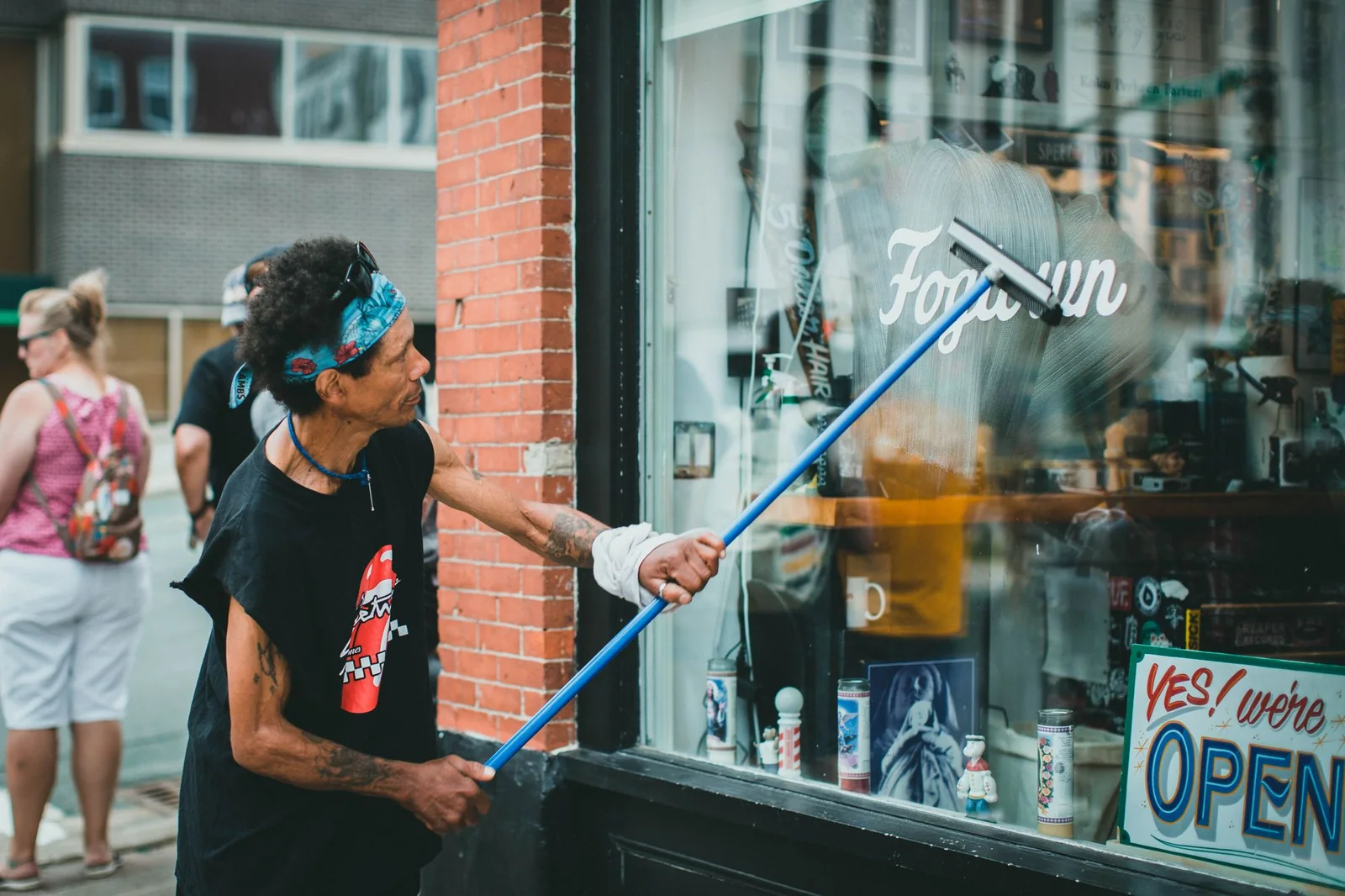 Window cleaner using a squeegee pole on a storefront window